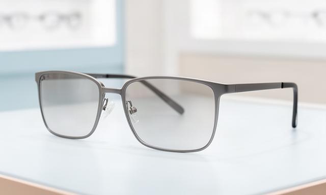 Korrektur-Sonnenbrille mit grauem Gestell in einer hellen Optikumgebung